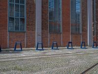 a row of blue tables sitting next to train tracks in front of a building with windows