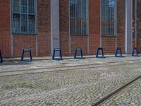 a row of blue tables sitting next to train tracks in front of a building with windows