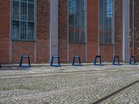 a row of blue tables sitting next to train tracks in front of a building with windows