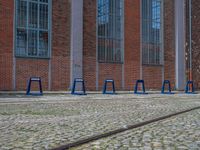 a row of blue tables sitting next to train tracks in front of a building with windows