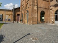 two large brick buildings and one smaller building with two doors, and a sidewalk with bricks and brickwork