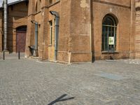 two large brick buildings and one smaller building with two doors, and a sidewalk with bricks and brickwork