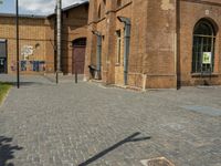 two large brick buildings and one smaller building with two doors, and a sidewalk with bricks and brickwork