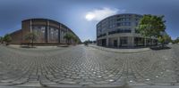 a 360 - view of two buildings near each other on a city street with cobblestones