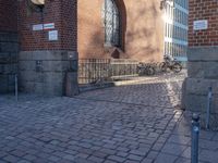 a metal pole sitting next to a brick building with arches on it and an ornate iron gate in front