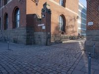 a metal pole sitting next to a brick building with arches on it and an ornate iron gate in front