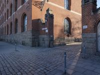 a metal pole sitting next to a brick building with arches on it and an ornate iron gate in front