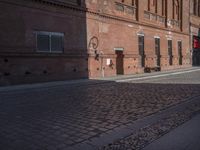 a building with a clock next to the side of it's walls and a person walking by it on a paved sidewalk