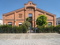 a building with brick walls and a fence and an iron gate next to a sidewalk