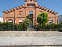 a building with brick walls and a fence and an iron gate next to a sidewalk