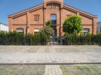 a building with brick walls and a fence and an iron gate next to a sidewalk