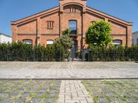 a building with brick walls and a fence and an iron gate next to a sidewalk