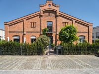 a building with brick walls and a fence and an iron gate next to a sidewalk