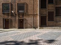 an image of a large brick building with windows in it that are empty on a cobblestone area