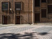 an image of a large brick building with windows in it that are empty on a cobblestone area