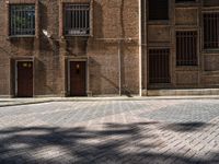 an image of a large brick building with windows in it that are empty on a cobblestone area