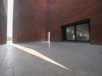 the inside of a brick building with a door and a window in it, and sunlight streams through the door