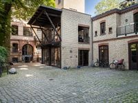 an old brick building with bicycles sitting in the courtyard outside the house and two bikes are parked on the pavement