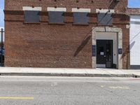 an abandoned brick building sitting across the street from a parked car and a fire hydrant