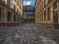 a sidewalk with chairs next to the brick building on the side, some have stairs and some buildings in the background