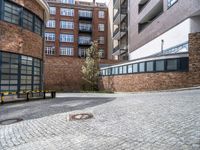 a stone paved courtyard area with an empty parking space and a building in the background