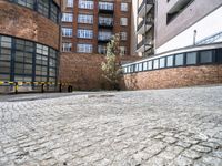 a stone paved courtyard area with an empty parking space and a building in the background