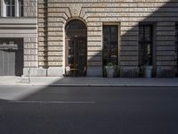 the building has a wooden door and large windows on the outside wall of it in the sunlight