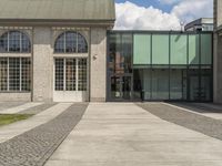 the walkway is paved to the ground where a building sits outside, with several windows