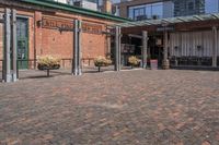 a view of a building with brick pavers and a patio area with seating on top