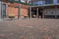 a view of a building with brick pavers and a patio area with seating on top