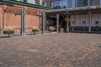 a view of a building with brick pavers and a patio area with seating on top