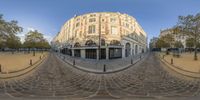 a fisheye view of an old fashion building on the edge of a street, in a city square