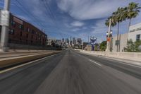 a long city street is shown from the side view mirror of a vehicle as it drives past several palm trees