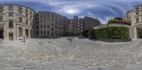 three buildings and a cobblestone road in a city center as reflected by this circular fisheye lens