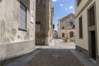 a street with two story buildings in it and the sky over it and some cobblestones on the sidewalk