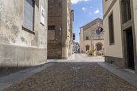 a street with two story buildings in it and the sky over it and some cobblestones on the sidewalk