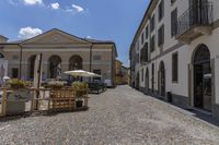 an empty cobble road is shown with a table and umbrellas next to it