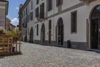 empty courtyard with flower boxes, chairs and umbrellas in front of a white building