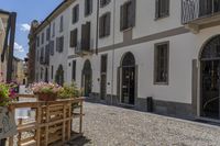 empty courtyard with flower boxes, chairs and umbrellas in front of a white building