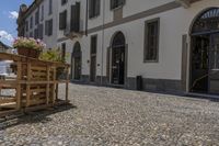 empty courtyard with flower boxes, chairs and umbrellas in front of a white building