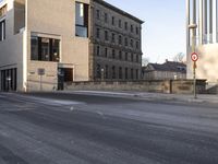 the large, empty sidewalk with multiple columns in front of the building with two signs