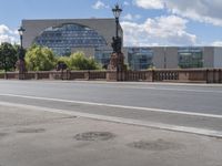 an empty road and some buildings in the background with clouds in the sky overhead,