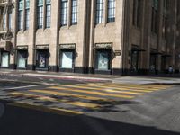 a yellow crosswalk on the street near some tall buildings in a city with people walking around