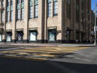 a yellow crosswalk on the street near some tall buildings in a city with people walking around