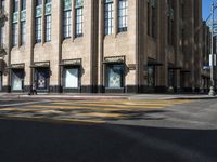 a yellow crosswalk on the street near some tall buildings in a city with people walking around