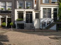 the courtyard is made out of brick and features lots of windows, a tree, a yellow chair and a street sign