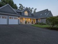 the house is lit up at dusk with a car garage door open on the driveway