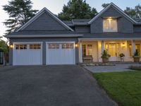 a large two story house with a long driveway in front and white garage doors on one side