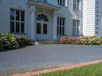 a woman stands outside an upscale building on a sidewalk with flowers in front of the door