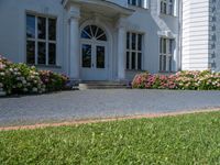 a woman stands outside an upscale building on a sidewalk with flowers in front of the door